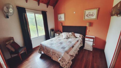 Dormitorio naranja con cama y ventana en R y C Nuestro Lugar en Villa General Belgrano
