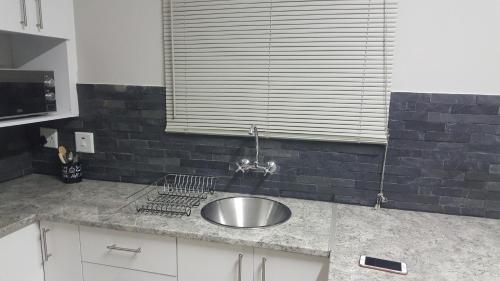 Una encimera de cocina con un fregadero y una ventana. en Tuna Self Catering, en Swakopmund