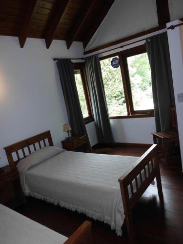 ein Schlafzimmer mit einem Bett und zwei Fenstern in der Unterkunft 4 SOLES in Villa Gesell