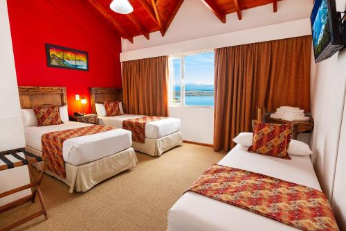 una camera d'albergo con tre letti e una finestra di Aikendor Hotel Panorámico a El Calafate