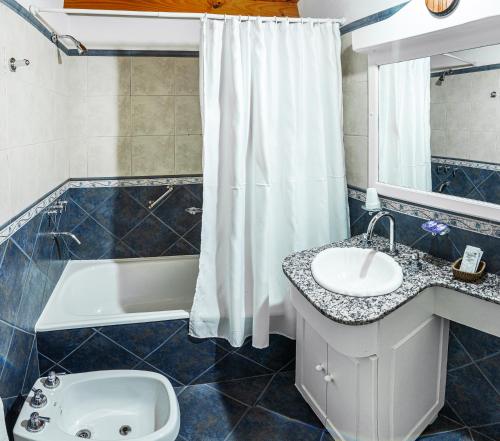 a bathroom with a sink and a tub and a toilet at Aikendor Hotel Panorámico in El Calafate