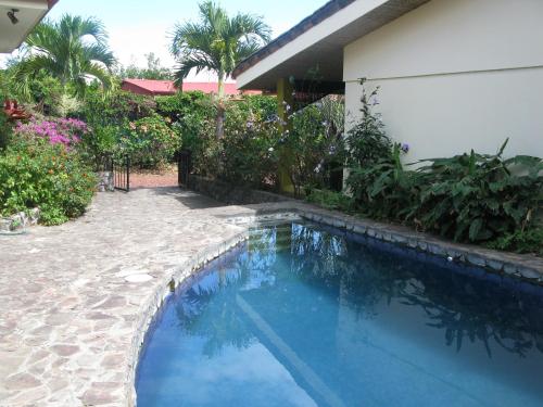 
a patio area with a pool and a garden at Dos Palmas Studio Apartments in Alajuela

