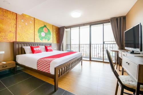 a bedroom with a bed with a television and a balcony at Super OYO 458 Nakorn Siam Boutique in Pattaya Central