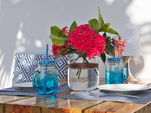 einen Tisch mit einer Vase mit roten Blumen darin in der Unterkunft ChuChubi Studio Apartment Bonaire in Kralendijk