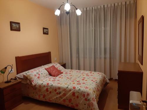 a bedroom with a bed with a flowered blanket and a window at BERGANTIÑOS 41,1º izd in Ponteceso