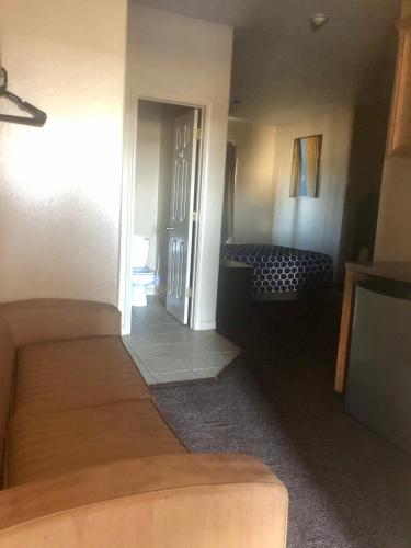 a room with a bed and a hallway with a couch at Lone Star Inn & Suites in Killeen