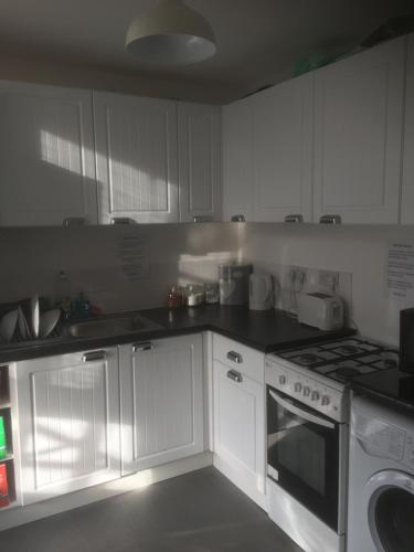 a kitchen with white cabinets and a stove top oven at Scotland Beds in Dundee