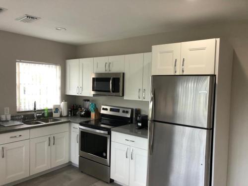 a kitchen with white cabinets and a stainless steel refrigerator at Coral Springs Paradise in Coral Springs