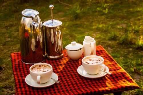 a table with two cups of coffee and a tea kettle at Serengeti Savannah Camps in Soronera