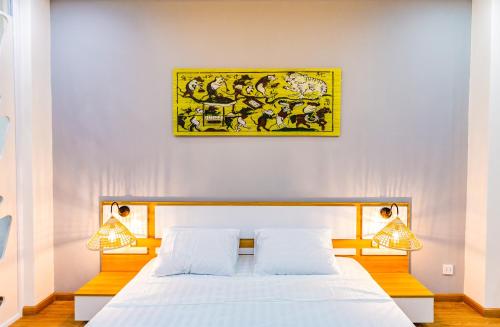 - une chambre avec un lit blanc et une peinture murale dans l'établissement Sai Gon Homestay, à Hô-Chi-Minh-Ville