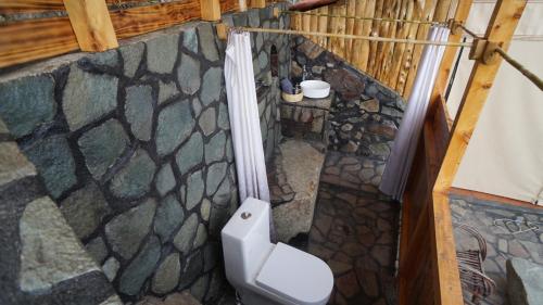 a bathroom with a toilet and a stone wall at EL PICNIC ATITLÁN in Tzununá