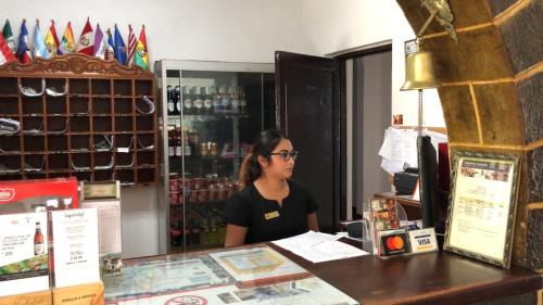 a woman sitting at a counter in a store at Hotel de Turistas Abancay in Abancay