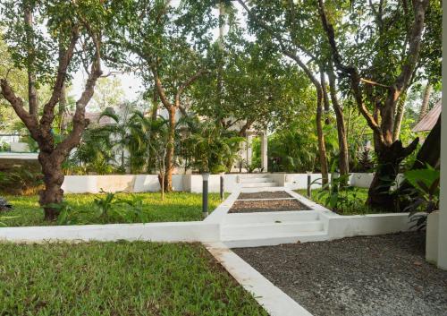 a garden with trees and a white fence at The Island Sanctuary Rock Pool Villa in Chorao