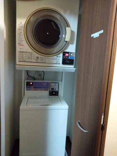 a microwave and a washer and dryer in a room at Nice Hostel Yahiro in Tokyo