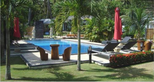 a swimming pool with palm trees and a red umbrella at Dream Estate Resort in Senggigi 
