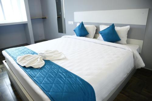 a large bed with blue and white sheets and blue pillows at The Base Inn (where convenience meets luxury) in Pondicherry