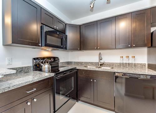 a kitchen with dark wood cabinets and stainless steel appliances at Ocean Beach Condo 3BR On the Sand 911 in Fort Lauderdale