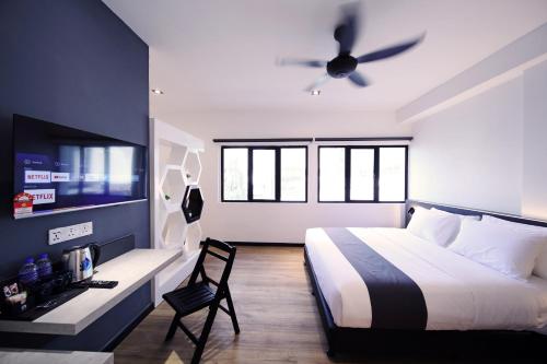 a bedroom with a bed and a desk with a tv at ARENA Boutique Hotel Kuala Terengganu in Kuala Terengganu