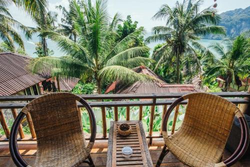 two chairs and a table on a balcony with palm trees at Railay Garden View Resort in Railay Beach