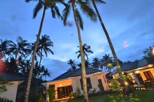 a house with palm trees in front of it at Dream Estate Resort in Senggigi 