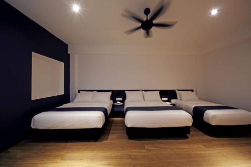 a room with four beds and a ceiling fan at ARENA Boutique Hotel Kuala Terengganu in Kuala Terengganu