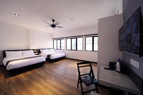 a bedroom with two beds and a chair in it at ARENA Boutique Hotel Kuala Terengganu in Kuala Terengganu