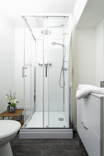 une douche avec une porte vitrée dans une salle de bain dans l'établissement LD - location Montluçon, à Montluçon