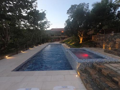 a swimming pool in a yard with a stone wall at Hotel Casas de Campo El Ciruelo in San Gil