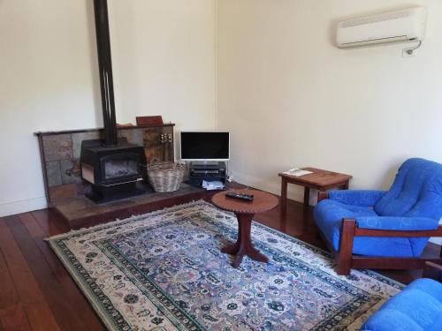 a living room with a blue chair and a table and a fireplace at Woodlands of Balingup Bush Cottages -Flora & Fauna focused in Balingup