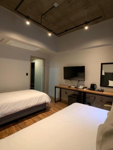 a bedroom with two beds and a desk with a television at Jeju Renaissance Hotel in Jeju