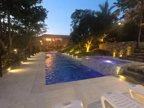 a swimming pool at night with chairs and lights at Hotel Casas de Campo El Ciruelo in San Gil