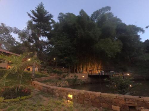 a bridge over a river next to a stone wall at Hotel Casas de Campo El Ciruelo in San Gil