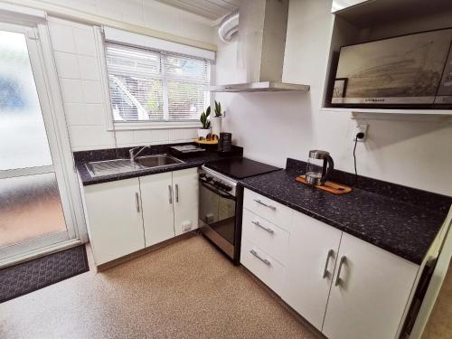 a kitchen with white cabinets and a black counter top at Lush & Co Auckland Bed & Breakfast in Auckland