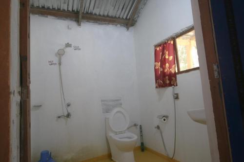 a white bathroom with a toilet and a sink at Wild Planet Eco Retreat in Bhurkīā