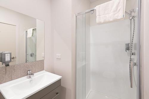 a white bathroom with a sink and a shower at Ramada Suites By Wyndham Victoria Street West in Auckland
