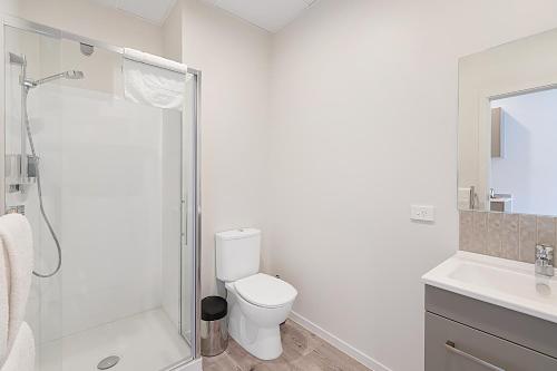 a white bathroom with a toilet and a shower at Ramada Suites By Wyndham Victoria Street West in Auckland