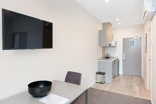 a room with a desk with a television on the wall at Ramada Suites By Wyndham Victoria Street West in Auckland