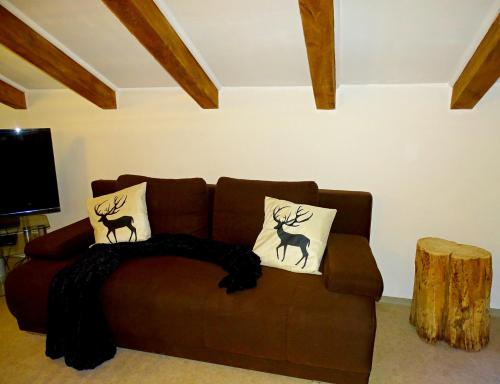 a brown couch with two deer pillows on it at Haus Schneeberg mit Hochkönig Card in Mühlbach am Hochkönig