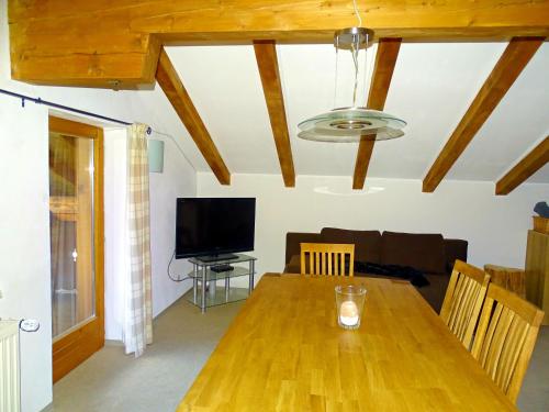 a living room with a wooden table and a television at Haus Schneeberg mit Hochkönig Card in Mühlbach am Hochkönig