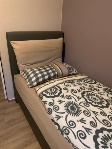 a bed with a black and white comforter and a pillow at landpension-dette in Berlingerode
