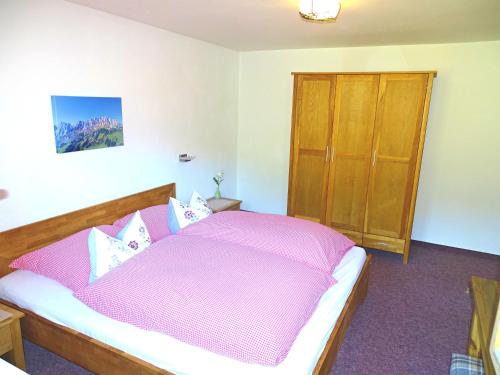 a bedroom with a pink bed and a wooden cabinet at Haus Schneeberg mit Hochkönig Card in Mühlbach am Hochkönig