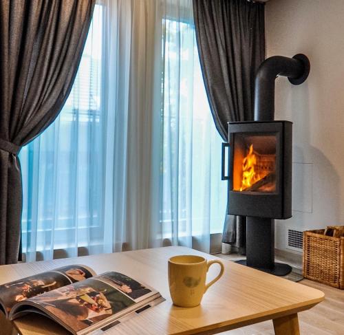 a fireplace in a living room with a book and a coffee cup at Nidos Namai in Nida