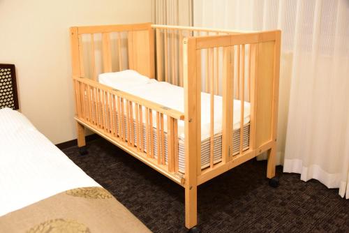 a wooden crib in a room with a bed at Hotel Sankyo Fukushima in Fukushima