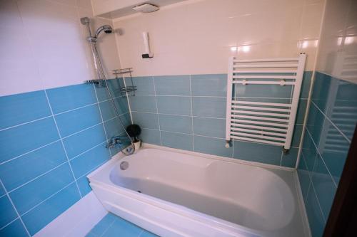 a bath tub in a bathroom with blue tiles at Pensiunea Ghiocelul in Avrig