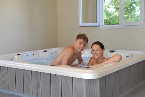 un homme et une femme dans une baignoire dans l'établissement Les Chalets de la Vingeanne, à Longeau