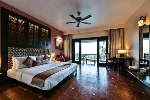 a bedroom with a large bed with a ceiling fan at The Fern Samali Resort in Dapoli