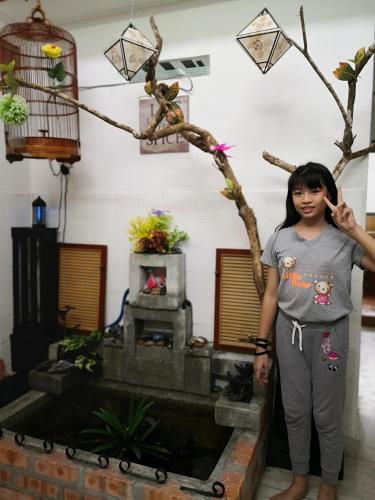 a girl standing in front of a fish pond at Hua Tang Homestay in Ipoh