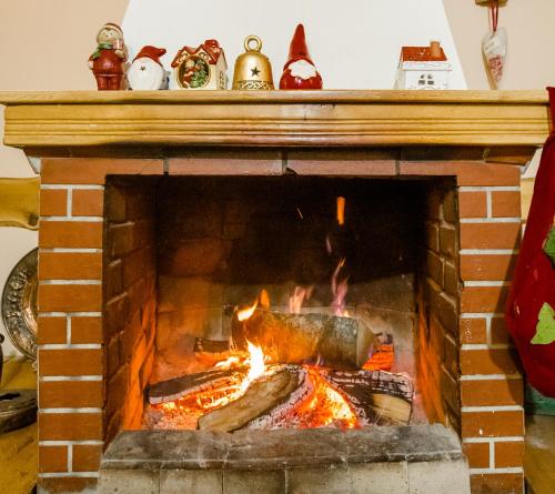 a brick fireplace with a fire in it at Pensiunea Ghiocelul in Avrig