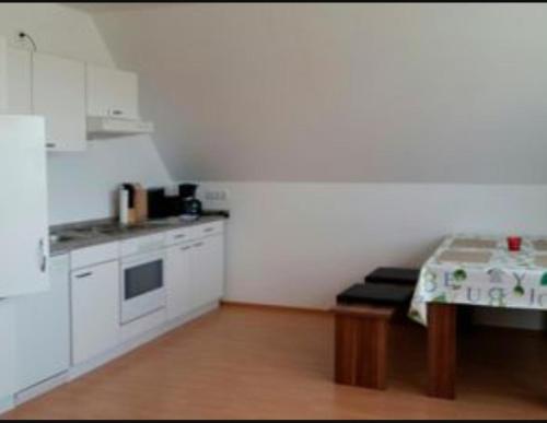 費馬恩的住宿－Ferienwohnung Heuer，白色的小厨房配有桌子和炉灶