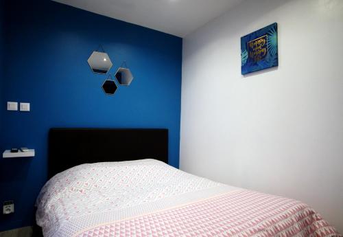 a bedroom with a bed and a blue wall at Studio confort N2 Valenciennes Wifi Netflix in Aulnoy